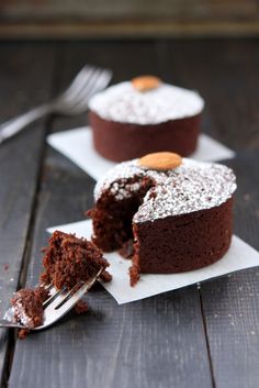 two pieces of chocolate cake on napkins with one piece cut out and the other half eaten