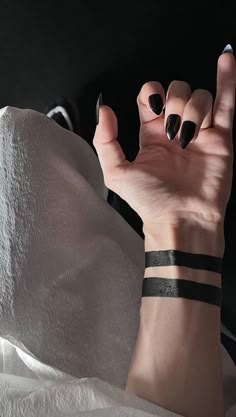 a woman's hand with black nail polish holding up the peace sign in front of her