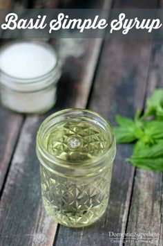 a glass jar filled with green liquid sitting on top of a wooden table next to a plant