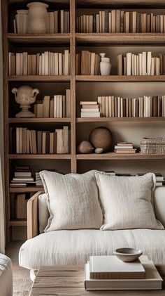 a white couch sitting in front of a book shelf filled with books and vases