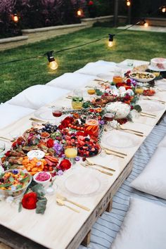 a long table is set up with plates and bowls full of food on it for a party