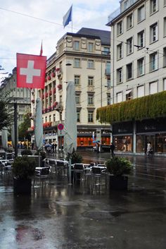 an empty street with tables and chairs in the rain