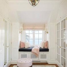 a window seat in the corner of a room with white walls and wood flooring