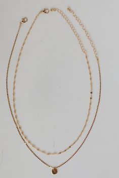 We're getting all the high roller vibes from the Emery Gold Layered Chain Necklace! This trendy necklace features two layers of gold chains with a circle charm on the end. Style the Emery Necklace with any outfit to instantly upgrade your look! Gold Plated Circle Charm Lobster Clasp with Extender Layer 1 | Length 7.5" Layer 2 | Length 7" Extender | Length 3" Double Strand Metal Necklace With Delicate Chain, Gold Layered Charm Necklace Choker, Dainty Metal Layered Necklace With Double Chain, Dainty Metal Double Chain Layered Necklace, Gold-tone Clavicle Chain Layered Choker Necklace, Gold-tone Layered Choker Necklace With Clavicle Chain, Gold-tone Layered Clavicle Chain Choker, Double Strand Delicate Chain Choker For Layering, Layering Double Chain Charm Choker