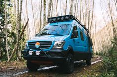 a blue van is parked in the woods