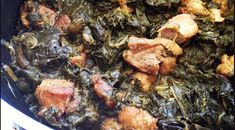 some meat and greens are cooking in a pot on the stove top with tongs