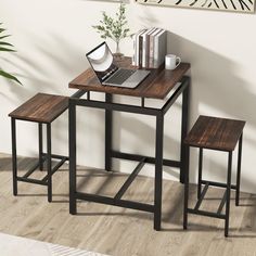 a laptop computer sitting on top of a wooden table next to two stools and a potted plant