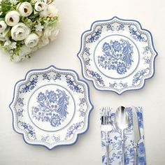 two blue and white plates sitting next to each other on top of a table with silverware