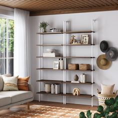 a living room filled with furniture and lots of shelves next to a large window on top of a hard wood floor