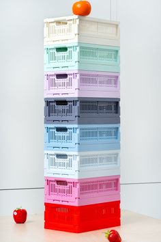 a stack of plastic crates sitting on top of a table next to an orange and some strawberries