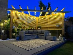 an outdoor living area is lit up at night with string lights on the pergolated roof