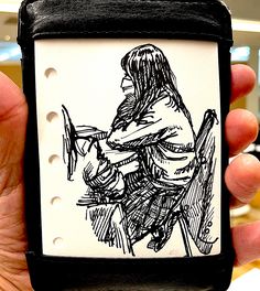 a drawing of a person sitting in a chair on a piece of paper that is being held by someone's hand