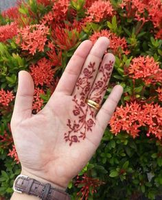 a person's hand with a ring on it and some flowers in the background