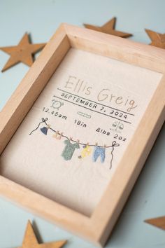 a baby's birth announcement in a wooden frame on a blue background with stars