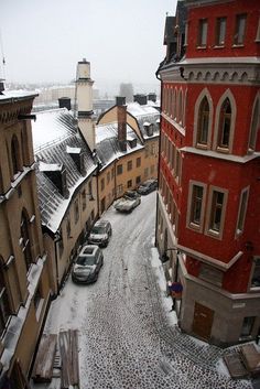 cars are parked on the street in front of buildings and snow covered ground with several windows