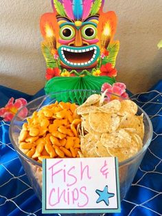 a bowl filled with chips next to a sign that says fish and chips on it