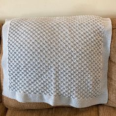 a white knitted blanket sitting on top of a couch