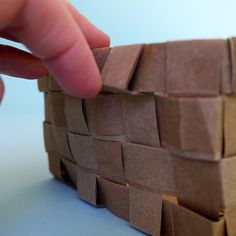 a hand is holding the edge of a piece of cardboard that looks like a basket