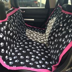 the dog seat covers are black and white with pink trimmings, which has paw prints on them