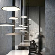 a long table with chairs and lights hanging from it's sides in a room