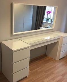 a white desk with drawers and a large mirror