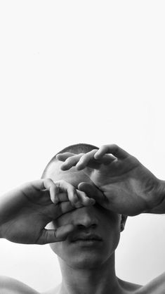 a black and white photo of a man holding his hands up to his face with both hands