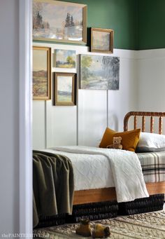 a bedroom with green walls and pictures on the wall above the bed, along with a teddy bear