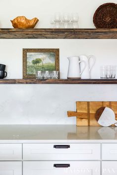 the shelves above the kitchen counter are filled with dishes and cups