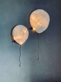 two white balloons with lights attached to them