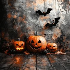 three carved pumpkins with bats hanging from them on a wooden floor in front of a grungy wall