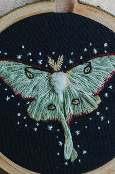 a close up of a embroidery on a piece of cloth with a butterfly in the middle