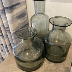 three glass vases sitting on top of a wooden table