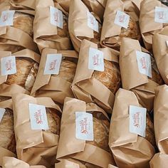 bread wrapped in brown paper are stacked on top of each other and ready to be sold