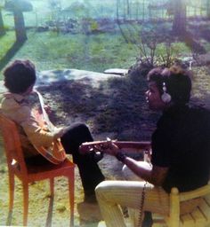 two people sitting on chairs talking to each other in a yard with grass and trees