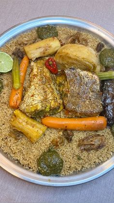 a plate filled with rice, vegetables and fish on top of a tablecloth covered table