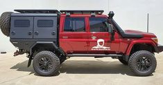 a red and black jeep parked in front of a building