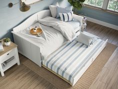 a bed with blue and white striped sheets in a room next to a wooden floor