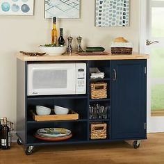 a kitchen with a microwave on top of a blue cabinet next to an open door