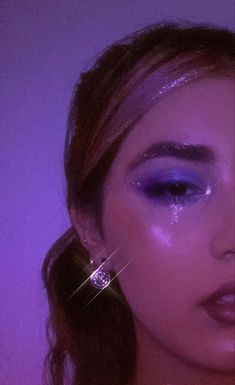 a close up of a woman with makeup on her face and purple lighting in the background