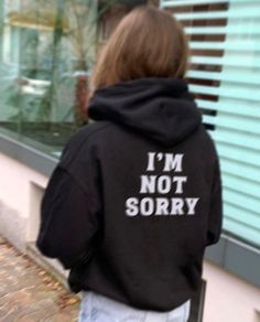 a person wearing a black hoodie that says i'm not sorry