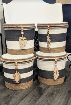 four black and white striped baskets with gold leaf decorations on the handles, two are stacked next to each other