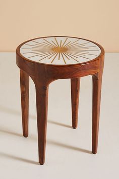 a small wooden table with a glass top and starburst design on the side