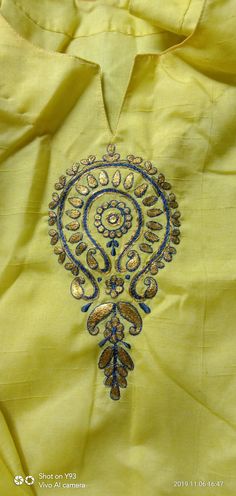 an embroidered yellow shirt with blue and gold details