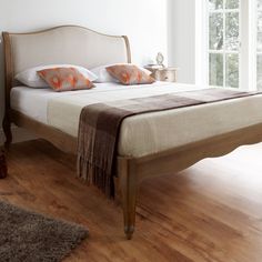 a bed sitting on top of a wooden floor next to a window