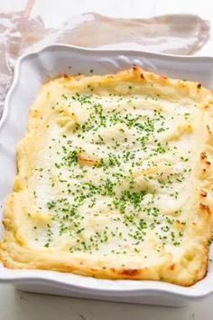 a square casserole dish with cheese and chives in it on a table