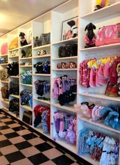 a room filled with lots of different types of clothing on shelving units next to a black and white checkered floor