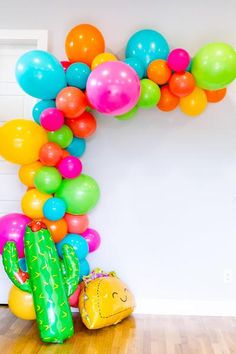 a cactus balloon arch is decorated with colorful balloons