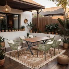 an outdoor dining area with potted plants on the side and a wooden table surrounded by chairs