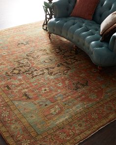 a blue couch sitting on top of a wooden floor next to a green chair and rug