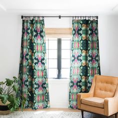 a chair sitting in front of a window next to a potted plant on top of a rug